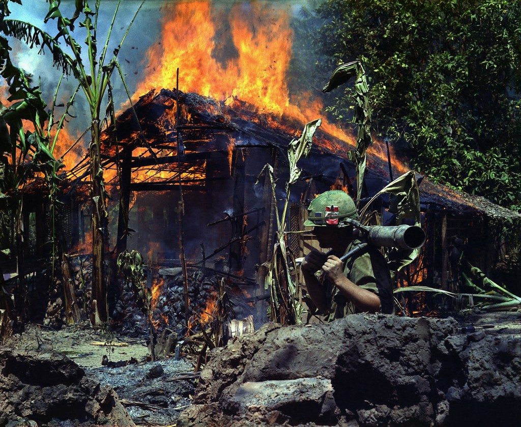 American soldier next to a burning building